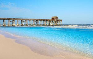 clear blue water and white sand beach with surf and long pier with tiki hut bar cocoa beach space coast feature