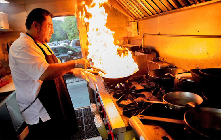 chef in food truck kitchen cooking with fire in pan at world food trucks kissimmee