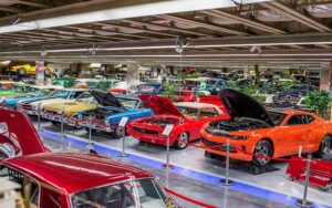 rows of colorful classic cars on display in warehouse space at tallahassee automobile museum