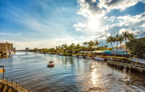 small boat on waterway with docked yachts buildings and sea wall in delray beach feature