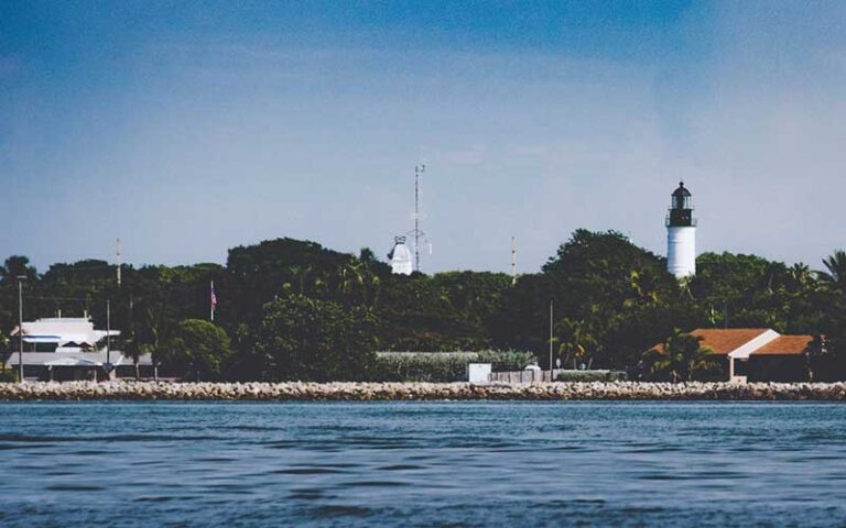 view from water of lighthouse and trees at key west lighthouse and keepers quarters museum