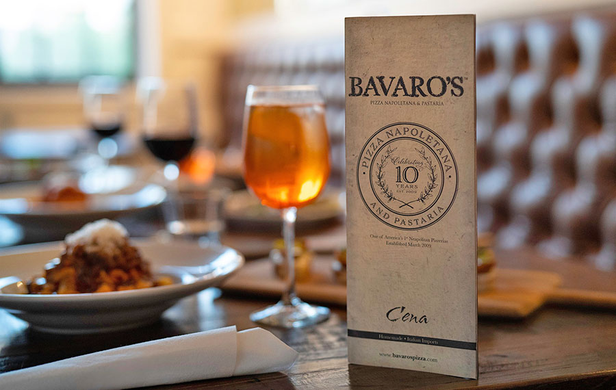 dinner table with booth entrees wine glasses and menu standing up with logo and 10 year anniversary at bavaros restaurant sarasota