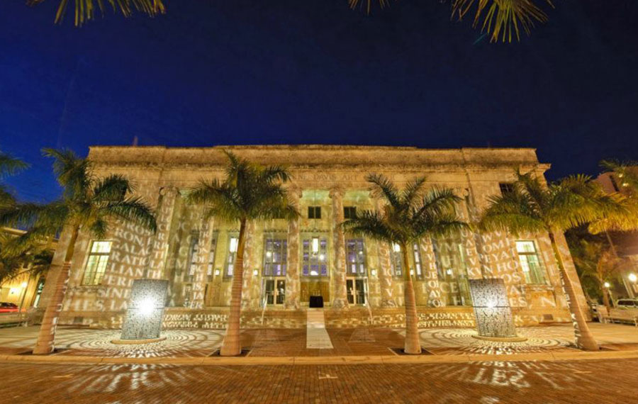 front exterior at night with lighted scroll sculptures casting words across columns at sidney berne davis art center fort myers