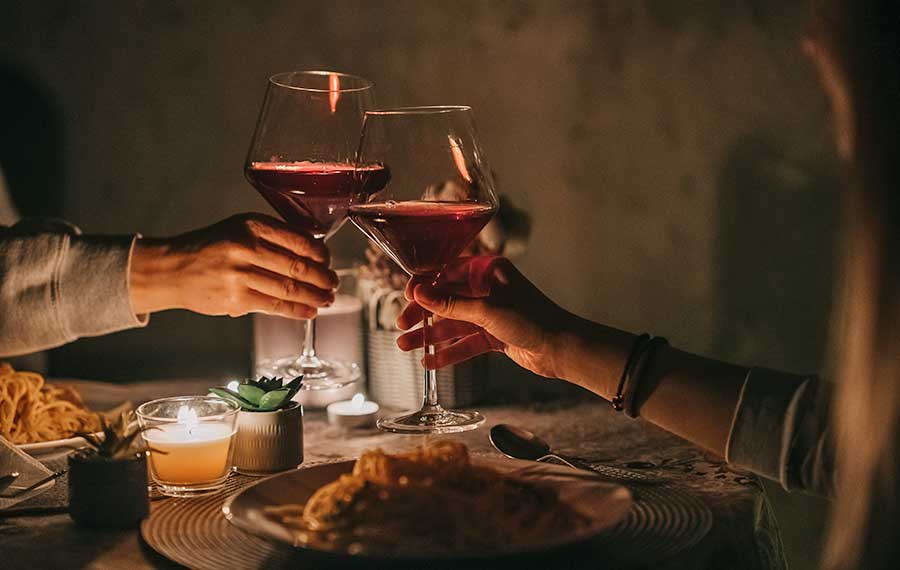 romantic candlelight dinner for two toasting wine glasses in restaurant setting