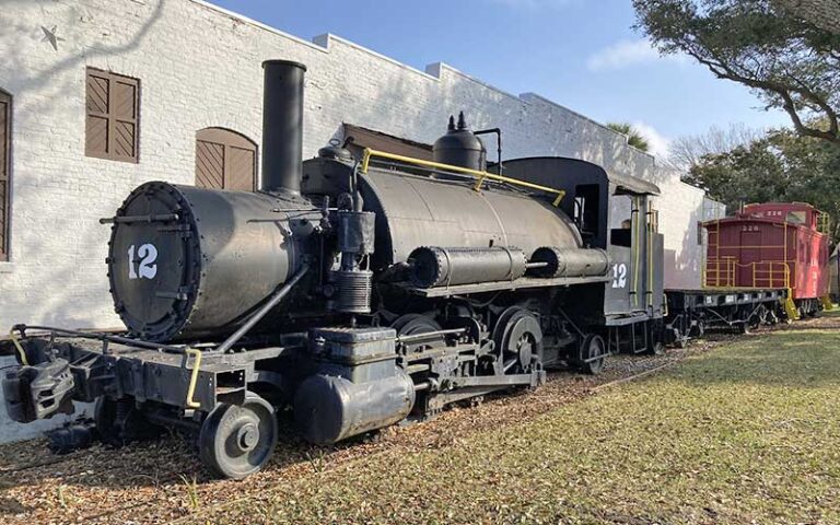 antique steam locomotive with red caboose at historic pensacola village
