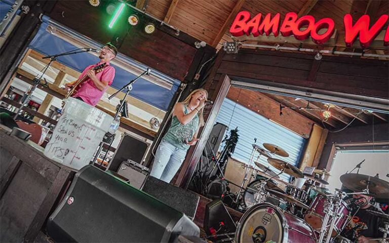 band performing in cabana style restaurant with bamboo willys sign at pensacola beach boardwalk