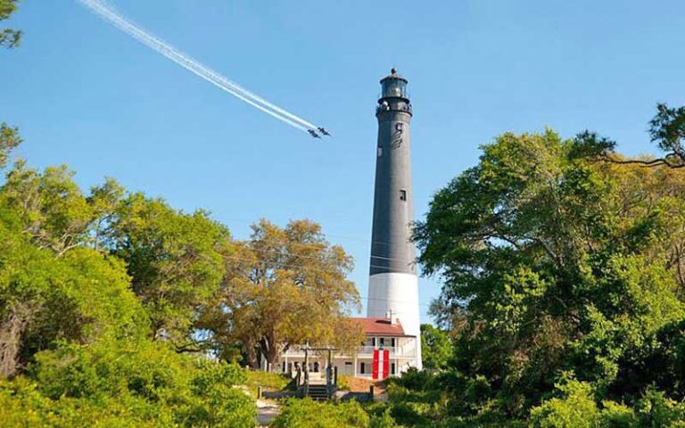 black and white lighthouse with airplanes flying by at pensacola lighthouse maritime museum