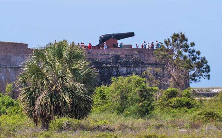 brick fortress wall with cannon and tourists at fort pickens pensacola