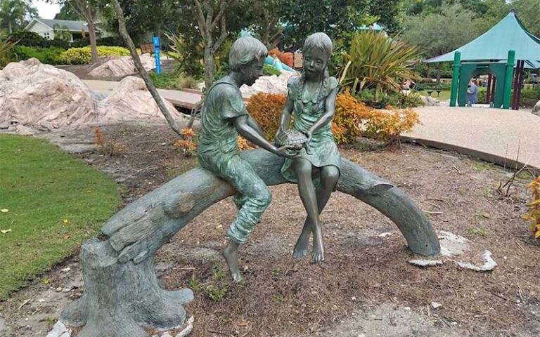 bronze sculpture of kids playing on tree at common playground lakeland