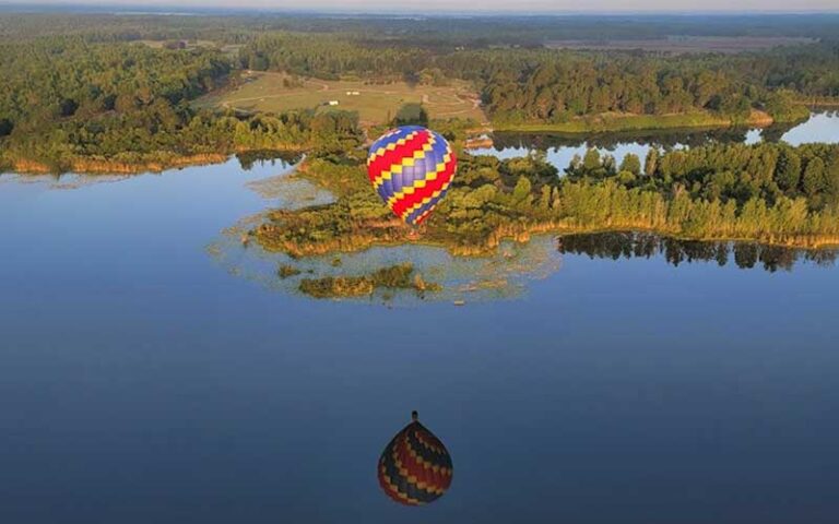 colorful hot air balloon reflected in lake with forests at air hound adventures davenport orlando