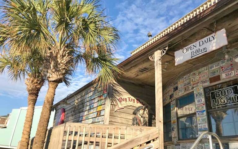 exterior of restaurant with palms and signs at peg leg petes pensacola