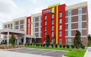 front exterior of hotel with red and green accents at home2 suites by hilton orlando south park
