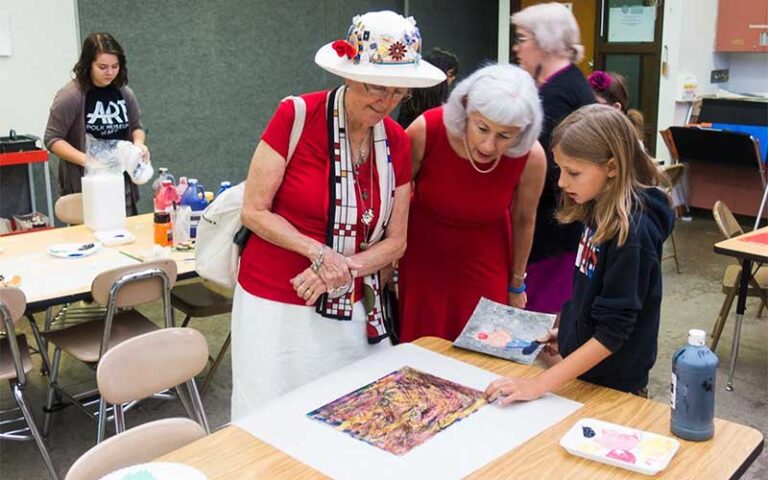 ladies looking at young girls artwork in class at polk museum of art lakeland