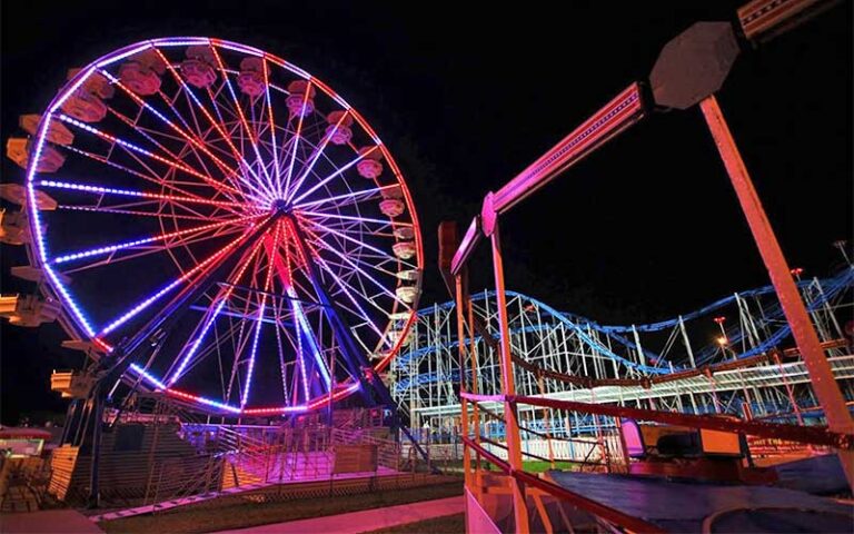 lighted ferris wheel and roller coaster at night at daytona beach boardwalk amusements