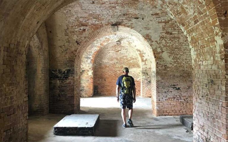 man with backpack standing in brick archway at fort pickens pensacola