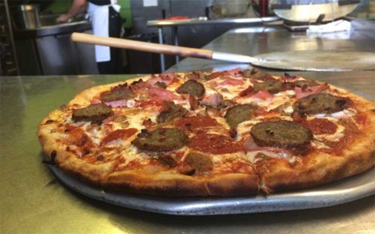 pizza with meat toppings on platter at ozone pizza pub pensacola