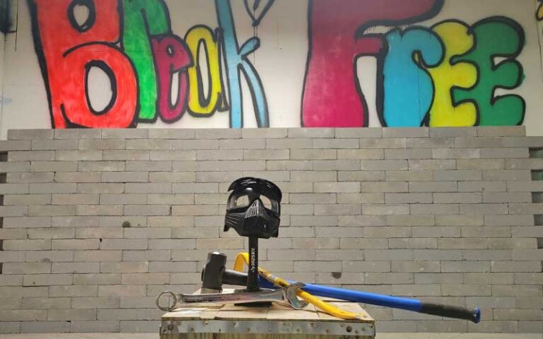 rage room setup with mask and sledgehammer and break free painted on wall at grizzly axes pensacola