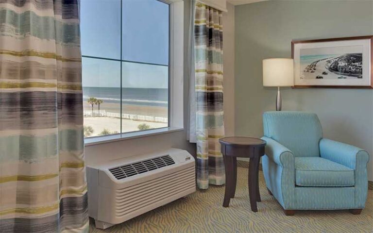 suite with chair and window overlooking beach at hilton garden inn daytona beach oceanfront