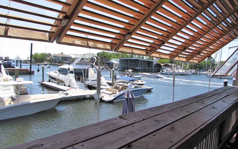 view from deck through shutter of marina boats at the oar house pensacola