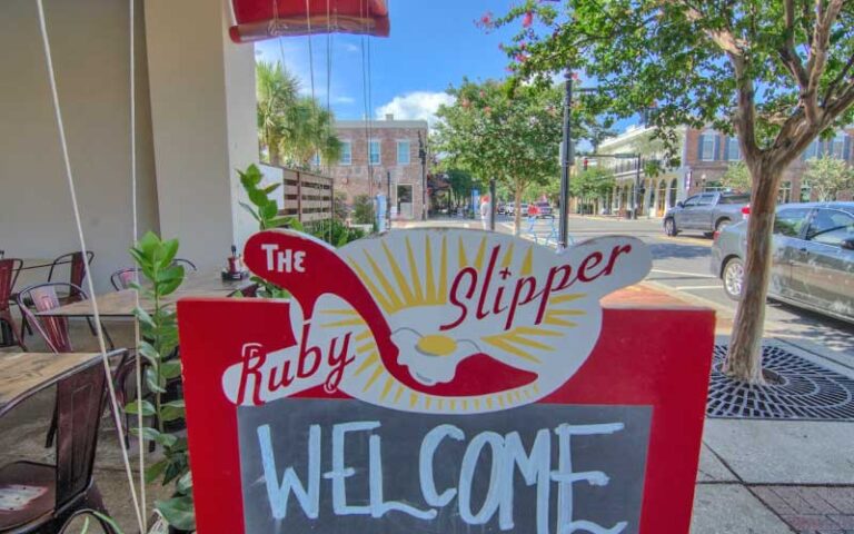 welcome sign with outdoor seating on sidewalk at ruby slipper pensacola