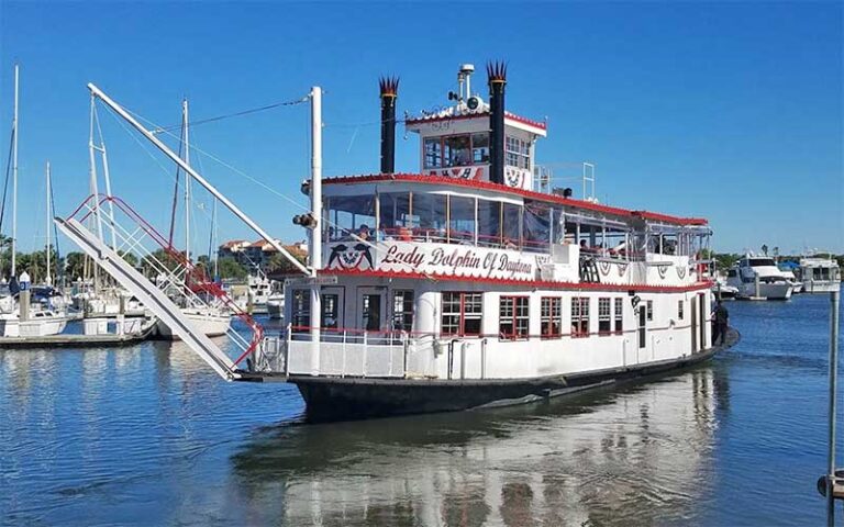 white and red riverboat in marina with clear sky at dine and cruise daytona beach