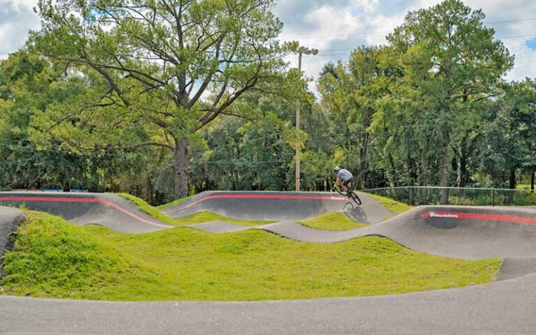 biker riding on paved pump bmx track in park area at tom brown park tallahassee