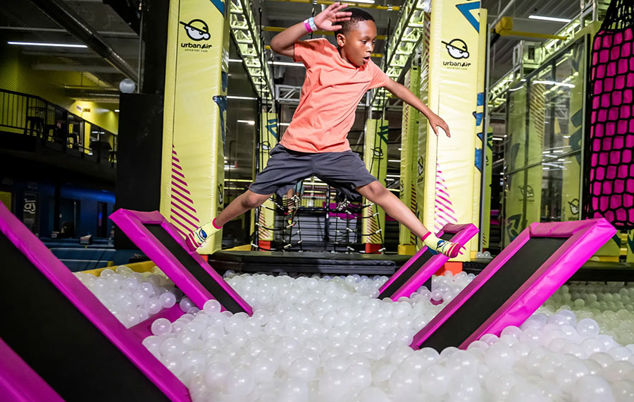 boy jumping through obstacle course with ball pit below at urban air trampoline adventure park wellington west palm beach