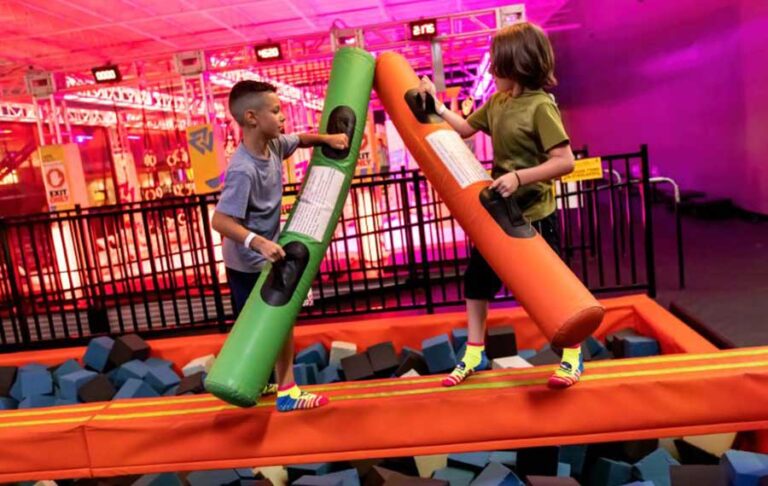 boys jousting with foam on balance beam over foam pit at urban air trampoline adventure park