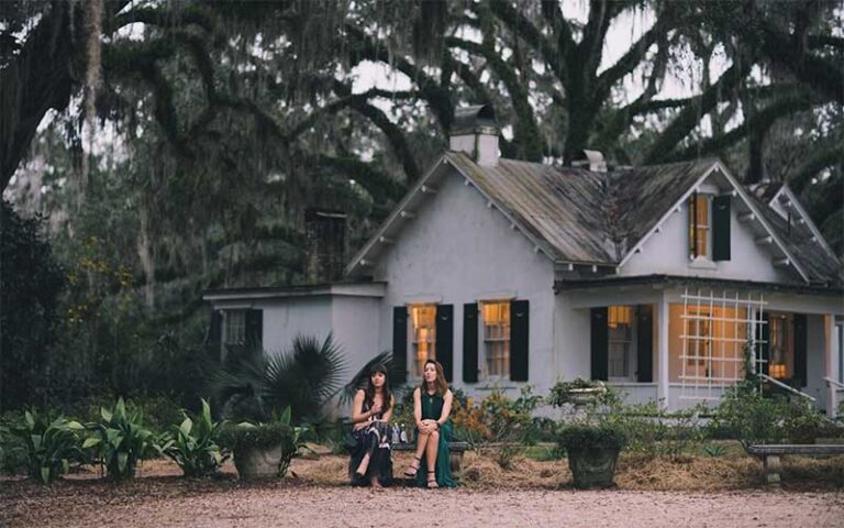 couple sitting on bench near historic home with trees at goodwood museum gardens tallahassee