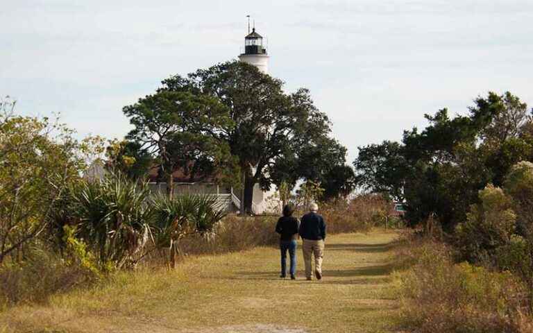 couple walking along trail with lighthouse in background at st marks lighthouse