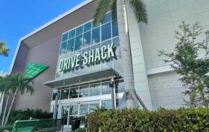 front exterior of building with signs and palm tree at drive shack west palm beach