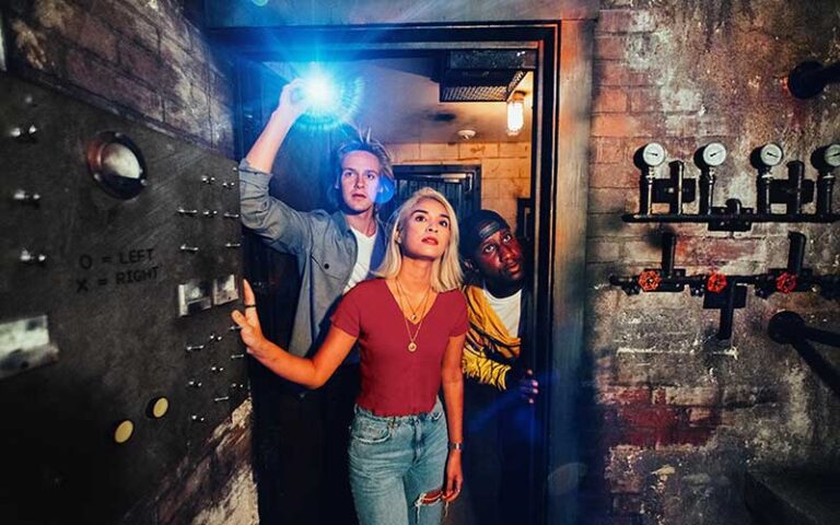 young men and woman with flashlight looking through prison door at the escape game