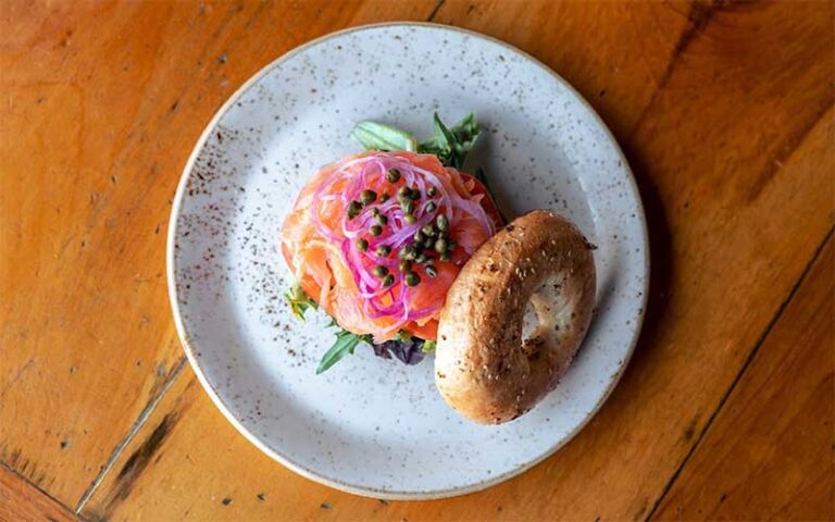 bagel sandwich with lox onions greens and capers on plate at marche burette omni amelia island