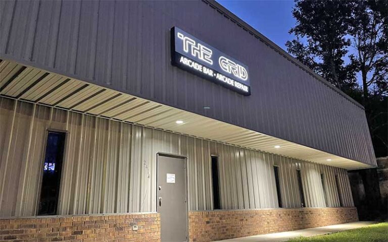 brown warehouse building with sign at night at the grid arcade pensacola