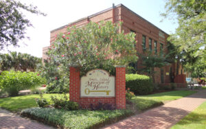 corner exterior of brick building with shrubs and sign at amelia island museum of history