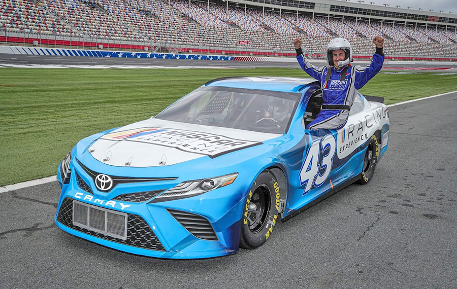 driver leaning out of stock car window in arena track at nascar racing experience