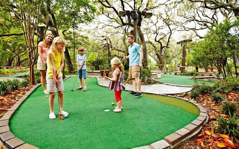 family playing mini golf in wooded area at omni amelia island resort fernandina beach