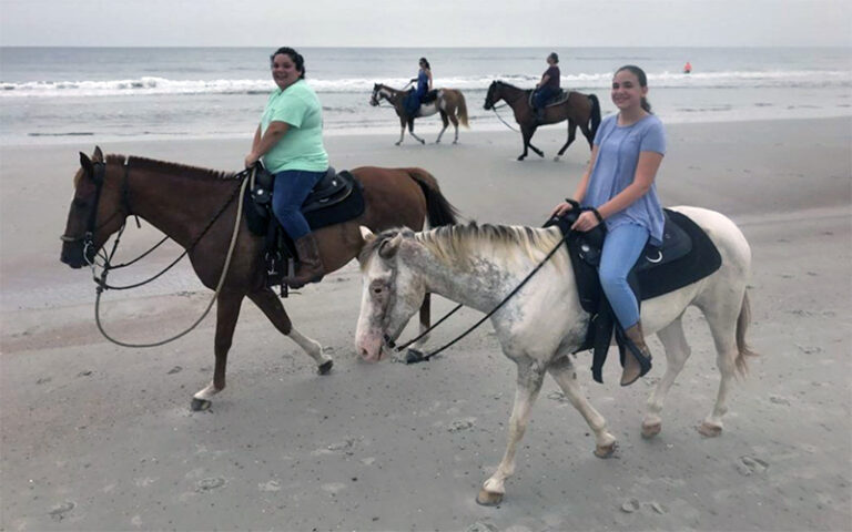 girl and woman riding horses along beach at amelia island horseback riding