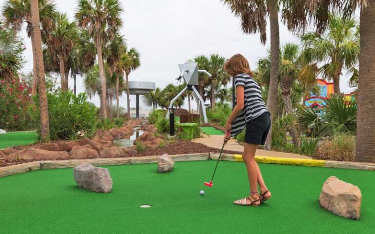 girl putting on hole with ufo statues at ufo golf pensacola beach