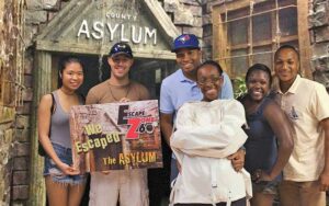 group holding sign escape game asylum at escape zone 60 pensacola