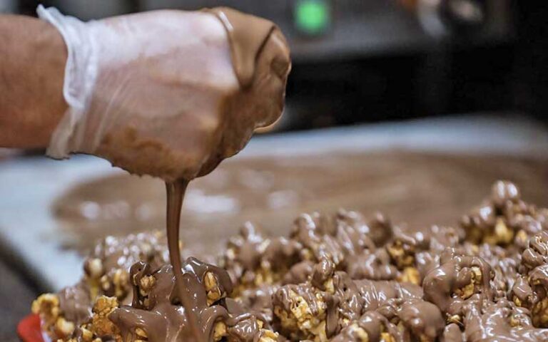 hand pouring chocolate onto popcorn at fantastic fudge fernandina beach amelia island