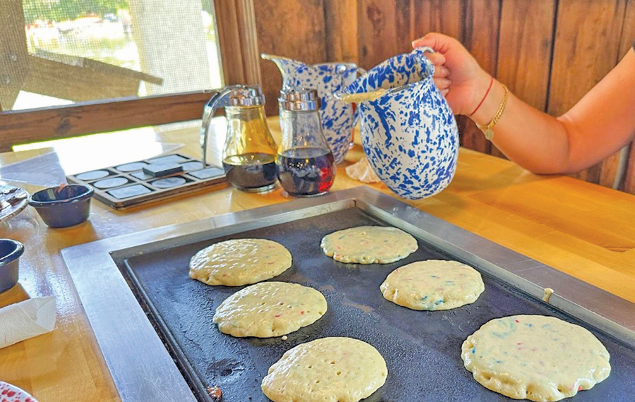 hand tipping pitcher of batter onto pancake griddle at old sugar mill at de leon springs