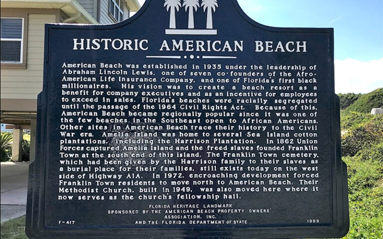 historic marker on beach with house behind at american beach amelia island