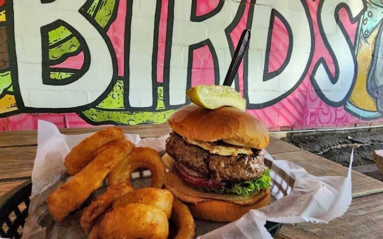 large burger with onion rings under sign at birds aphrodisiac oyster shack tallahassee