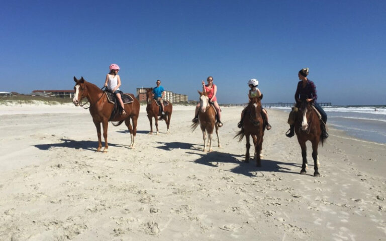 large group of horseback riders on white sand beach at amelia island horseback riding