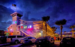 night exterior of restaurant with neon sign and flags at sliders seaside grill fernandina beach amelia island