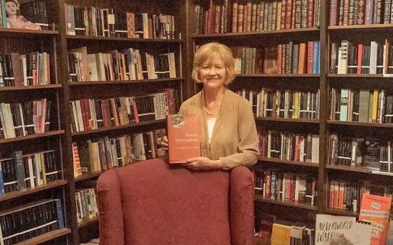 owner holding up book with walls of bookshelves at the book loft fernandina beach amelia island