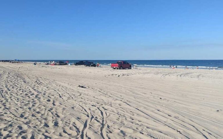 sandy beach with vehicles parked and clear sky at peters point beachfront park amelia island