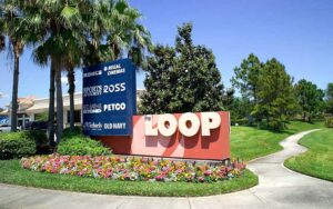 shopping center sign with stores and landscaping at the loop kissimmee
