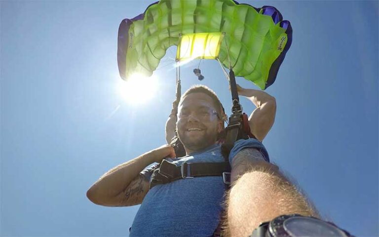 tandem skydiver selfie with yellow parachute and sun at skydiving jacksonville amelia island